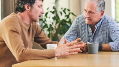 Elderly man in discussion with younger man at table