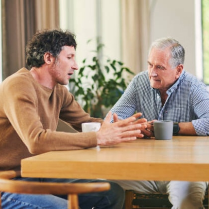 Elderly man in discussion with younger man at table