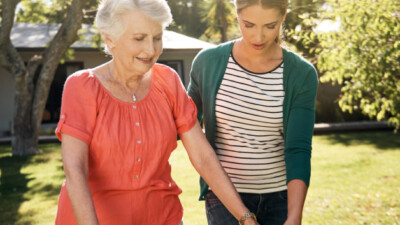 Daughter helping mother using walker